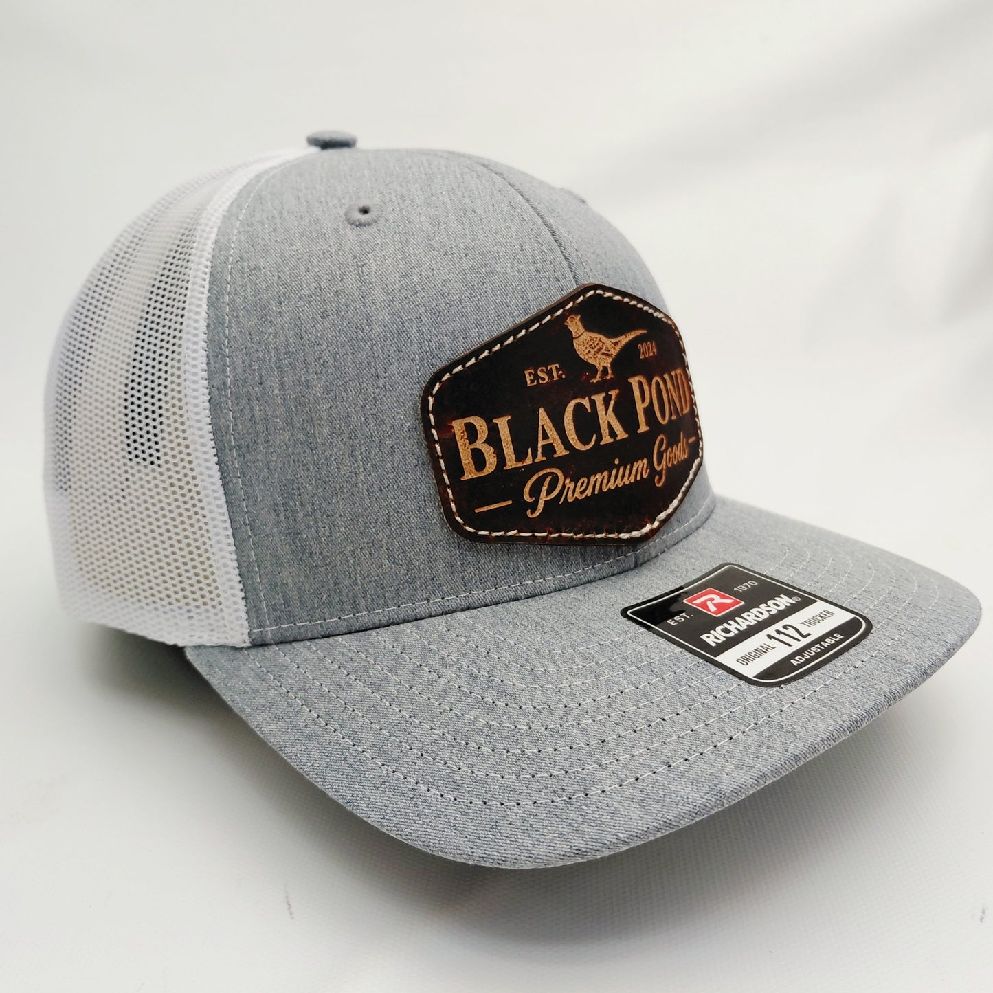 Right angled view of Black Pond pheasant leather patch Richardson 112 trucker hat in heather gray and white