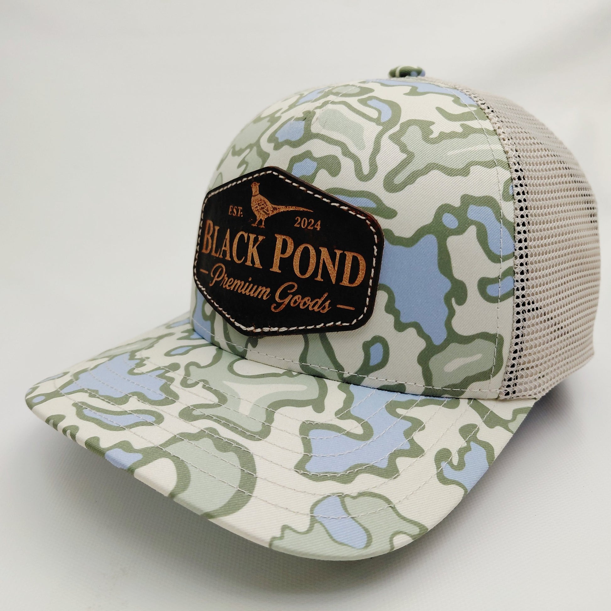 Left angled view of Black Pond pheasant leather patch Richardson 112 light camouflage trucker hat