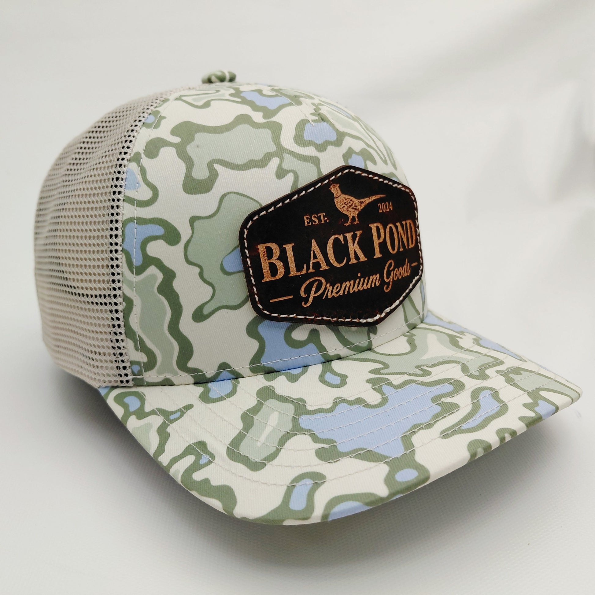 Right angled view of Black Pond pheasant leather patch Richardson 112 light camouflage trucker hat