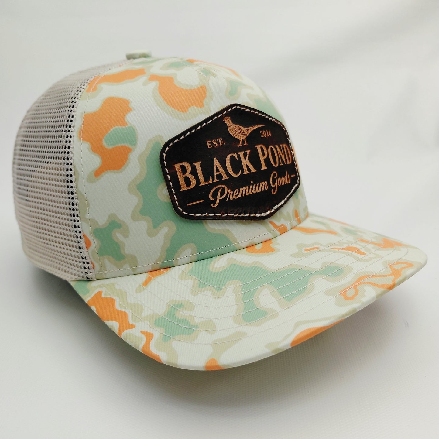 Right angled view of Black Pond pheasant leather patch Richardson 112 mint orange camouflage trucker hat