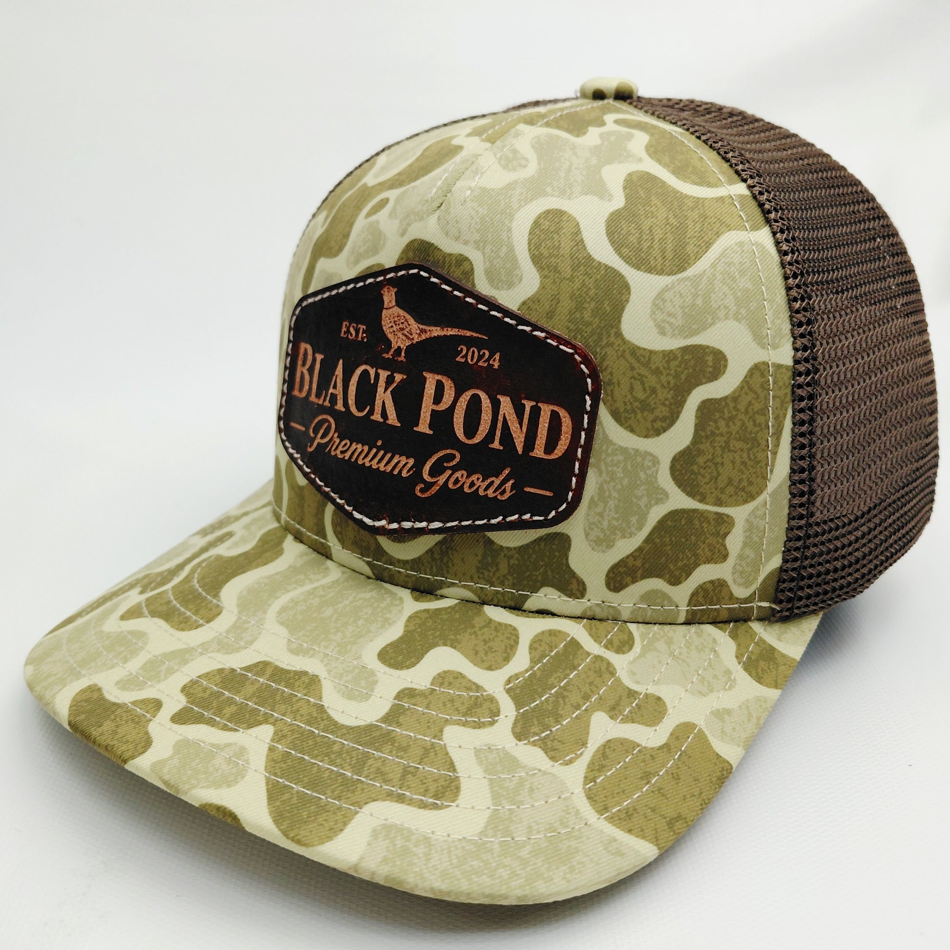 Left angled view of Black Pond pheasant leather patch Richardson 112 camouflage trucker hat