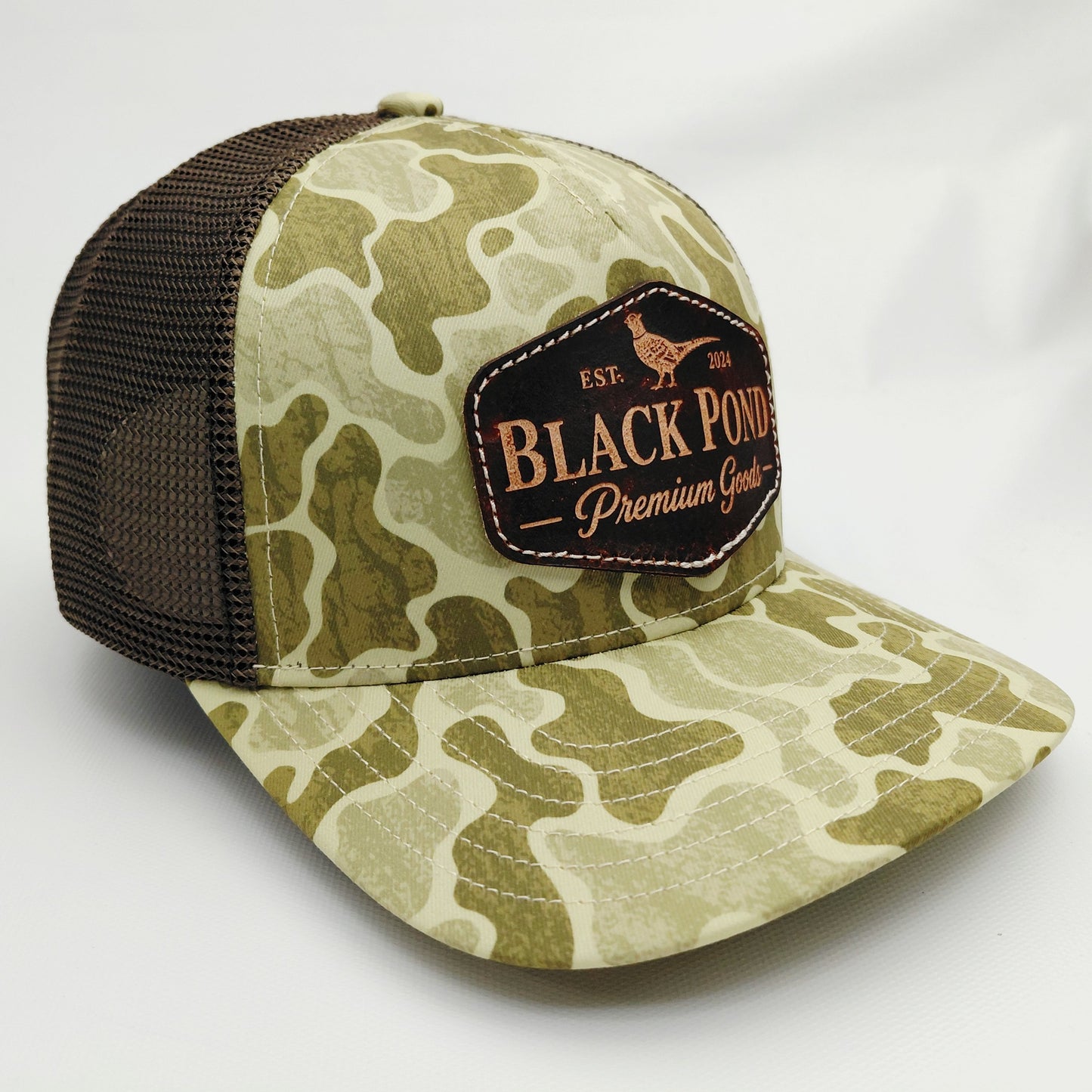 Right angled view of Black Pond pheasant leather patch Richardson 112 camouflage trucker hat