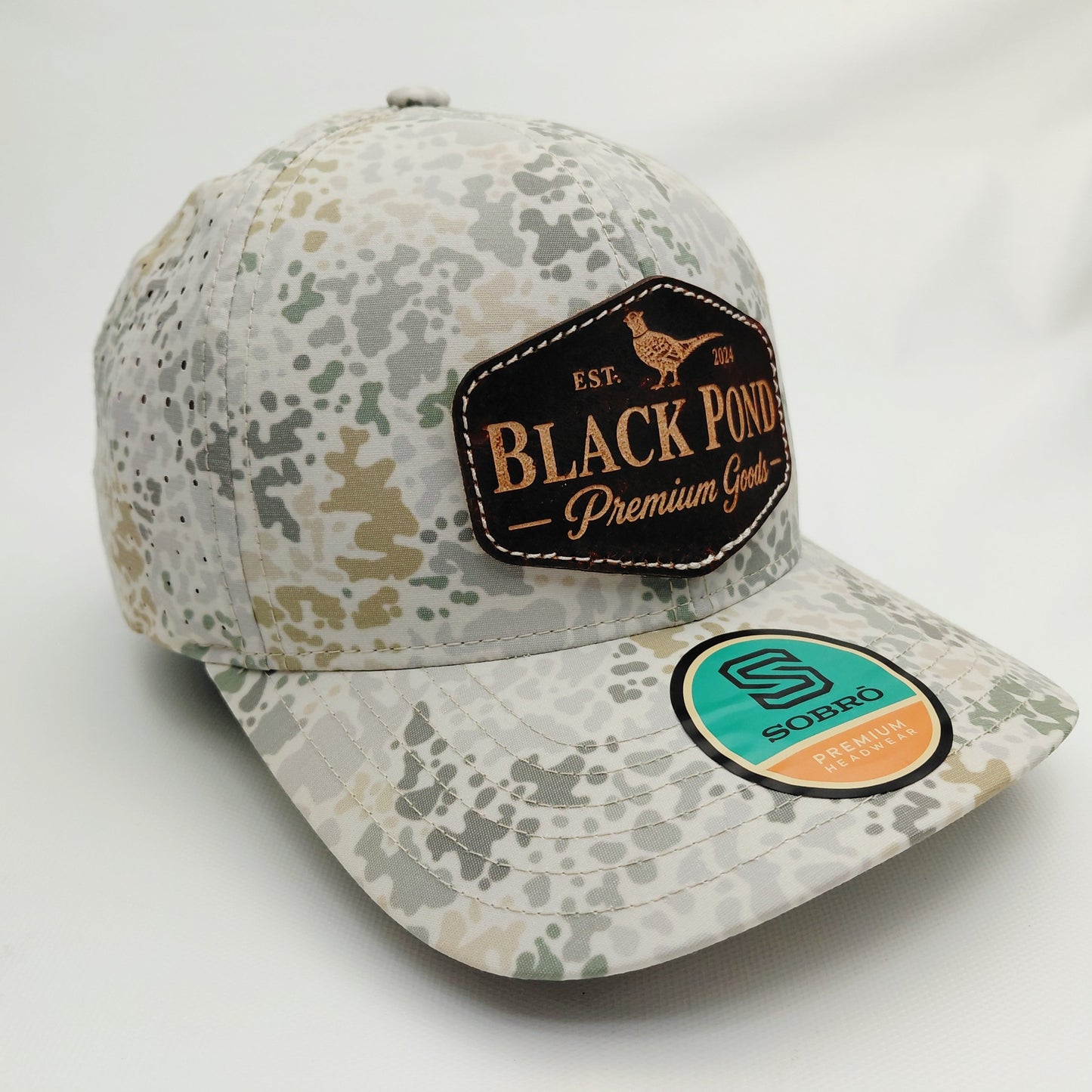 Right angled view of Black Pond pheasant leather patch SOBRO perforated camouflage trucker hat